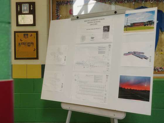 a large easel with a display of plans for an efficiency project at a middles school