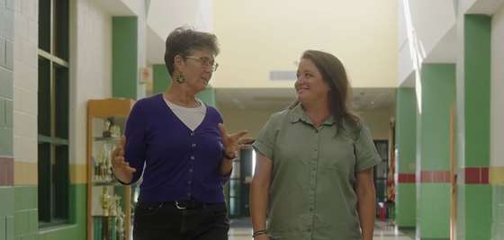 Cathy Reynolds and Holly Andersen walking the hallways of an elementary school in conversation