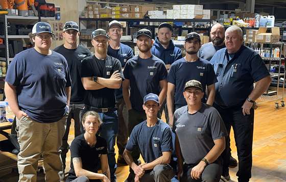 employees in dark blue work shirts psing for a group photo
