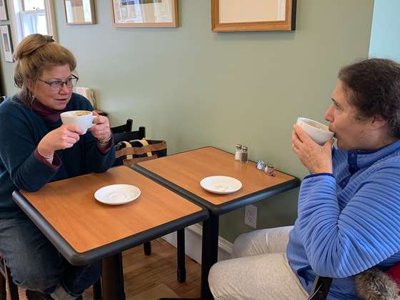 two women sitting at a cafe table enjoying conversation and coffee