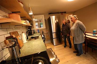Members of the public tour a kitchen in a newly renovated inn, with visitors to the right of the frame and energy-efficient appliances to the left of the frame