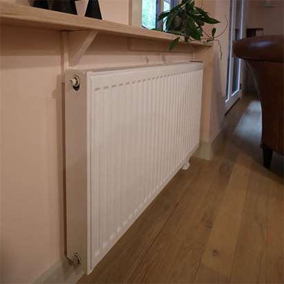 A white radiator sits snugly against a cream-colored wall.