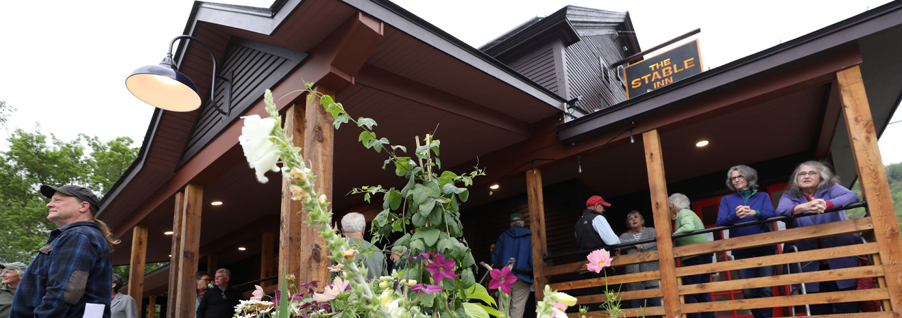 A photo of the Stable Inn with people enjoying the front porches