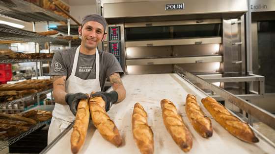 A King Arthur Flour baker displays freshly baked baguettes