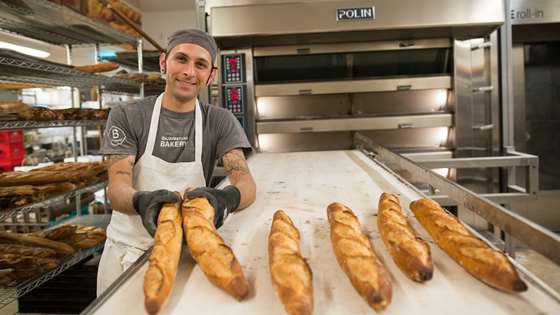 A King Arthur Flour baker displays freshly baked baguettes