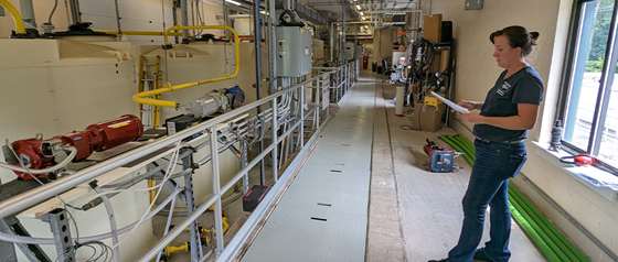 woman looking over air compressing equipment inside a water treatment facility