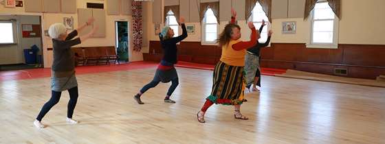 four women in practicing dance on a large hardwood dance floor 