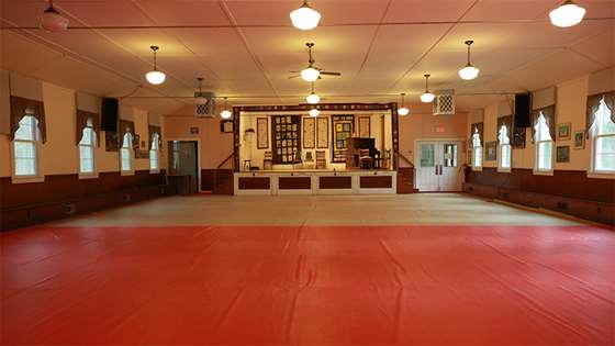 interior of Capital City Grange showing a hardwood floor small auditorium with a stage