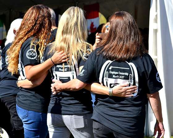 women with backs to the camera and arms around each other in matching shirts