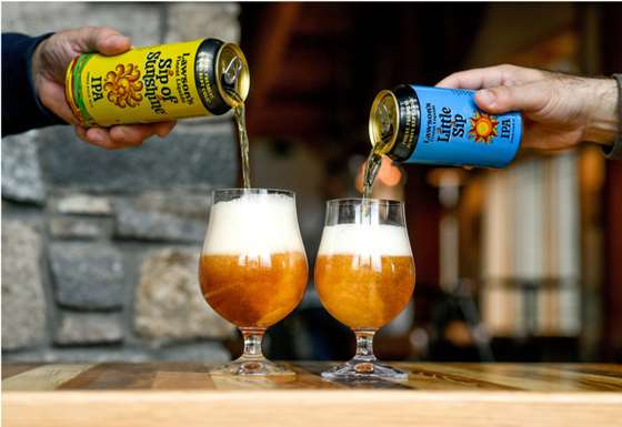 2 cans of beer being pored into glasses