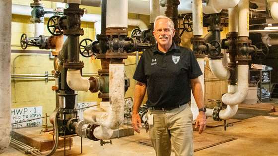 Dave Bullist stands in front of pumps in the school