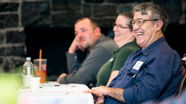 two men and a women laughing at a table