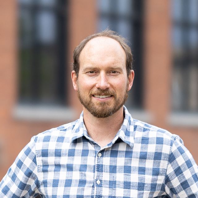 picture of a smiling white male wearing a blue plaid button down shirt