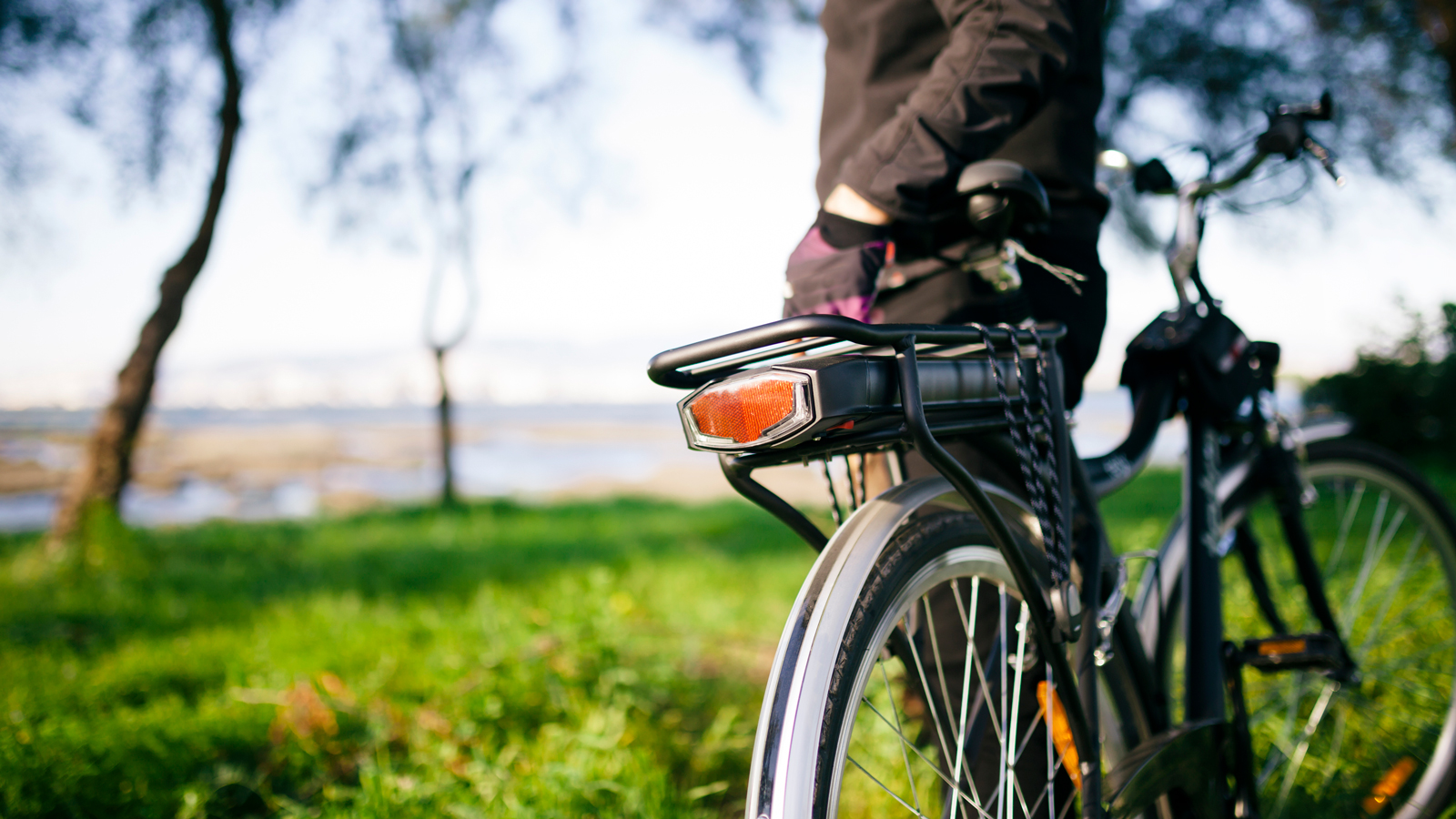 Bicyclist standing in a field next to electric bicycle